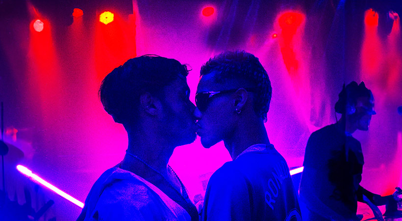 two-young-men-kiss-on-colourful-dancefloor