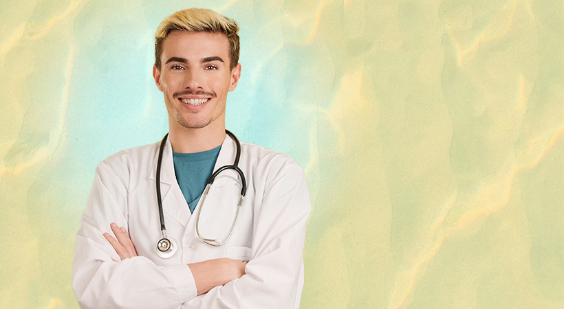 Gay doctor smiling at the camera standing with arms crossed