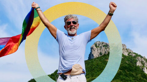 Gray-haired senior elderly man diabetic bisexuality with a beard and sunglasses holding a rainbow LGBTQIA flag on nature. Celebrates Pride Month, Rainbow Flag Day, gay parade