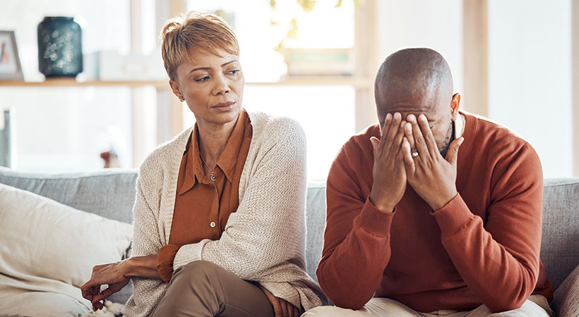 Divorce, stress and mature couple arguing on the sofa in the living room of their house. Frustrated, relationship problems and upset African man and woman speaking in the lounge of their home.