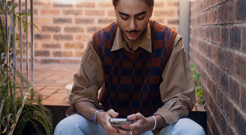 Arabic person using phone on steps to house