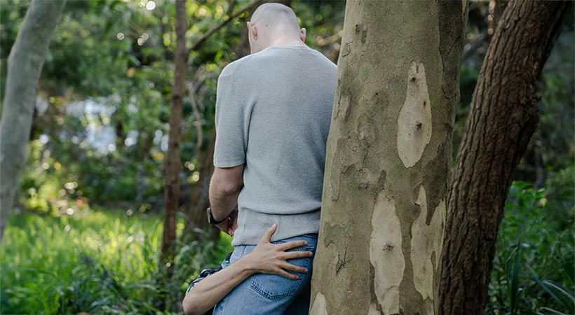 Bald man getting a blowjob with clothes on in a park