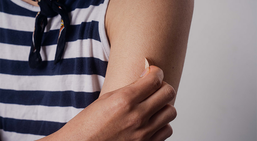 close-up-man-removing-injection-bandaid