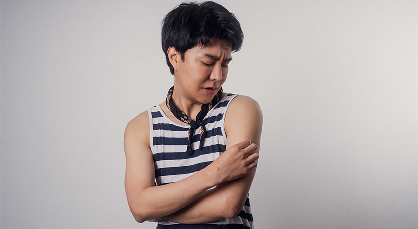 young-thai-man-in-striped-singlet-removes-bandaid-from-arm