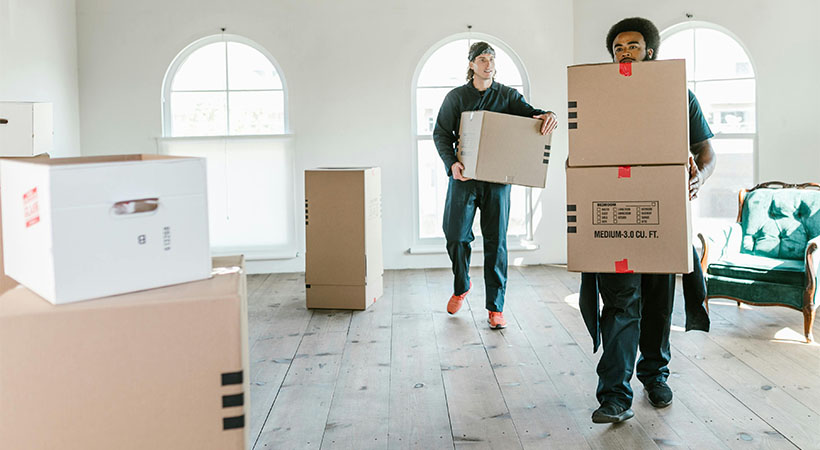 Two men carrying boxes into an apartment