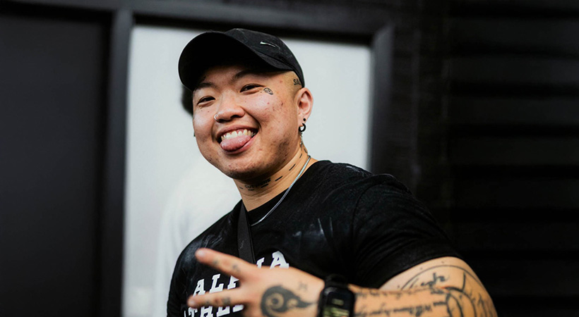 Chinese trans man smiling and throwing peace sign with hands
