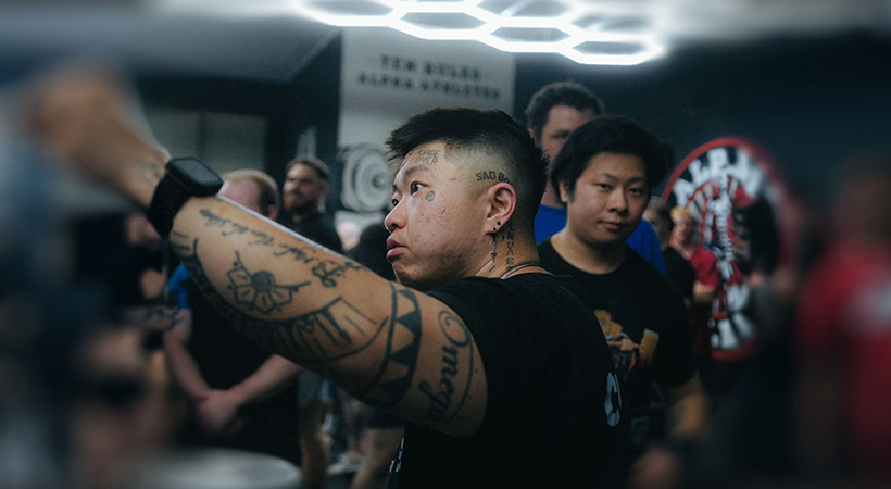 Chinese trans man with tattoos punching the air