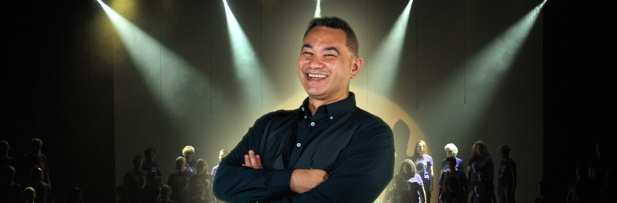 Maori comedian smiling with stage performance in background