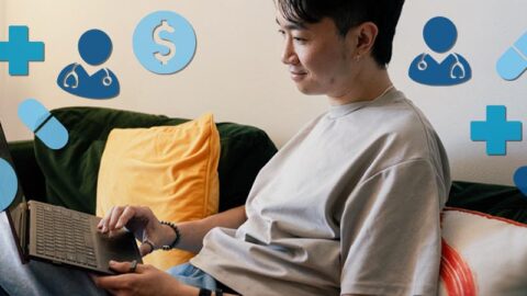 Chinese man on computer in living room with blue health icons floating