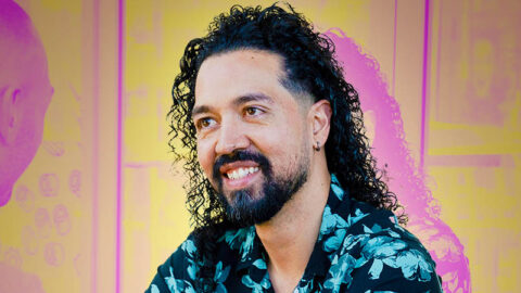 Colombian man smiling at figure, busy cafe background in pink and yellow duotone